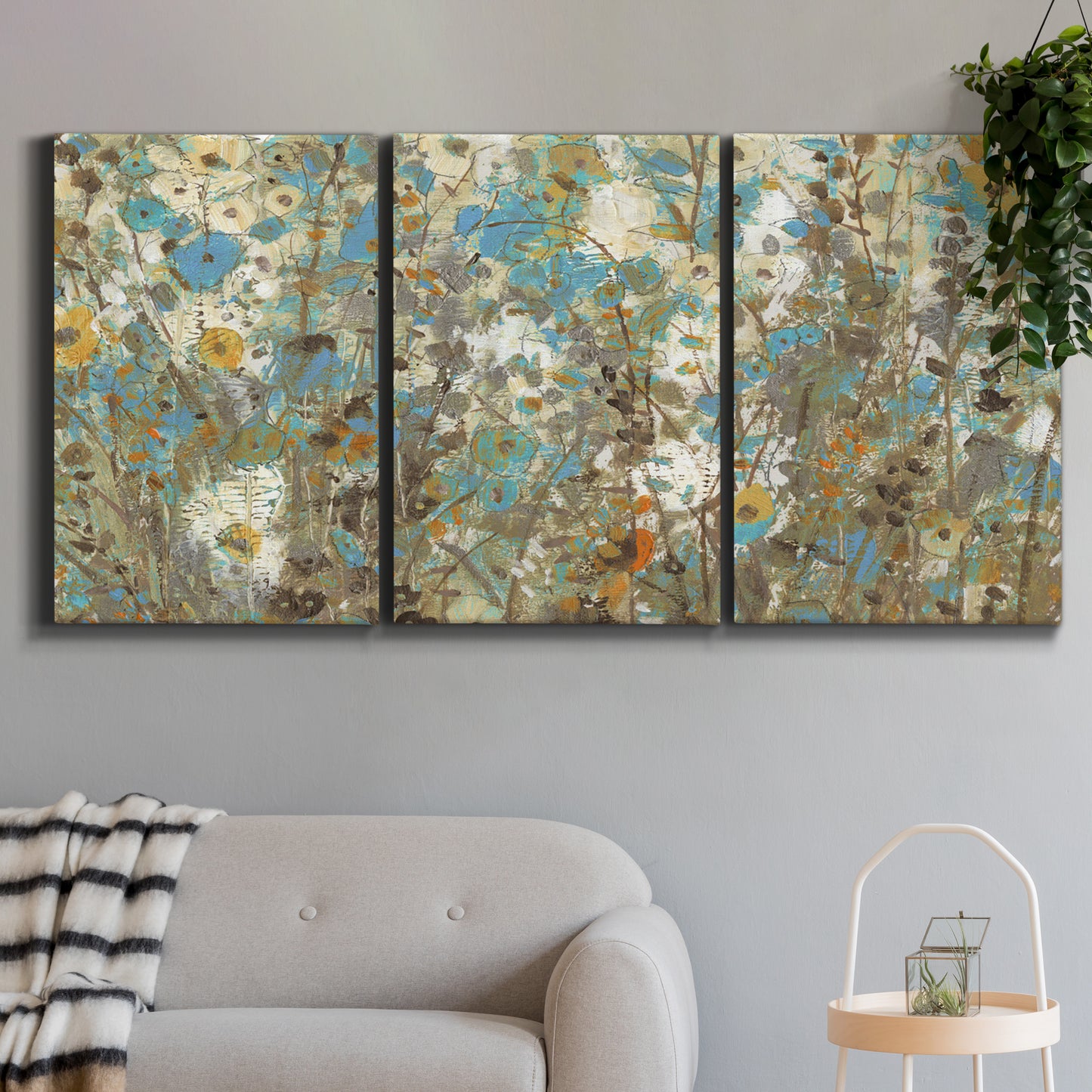 Three-panel canvas wall art featuring abstract flowering vine pattern, displayed in a modern living room above a sofa.