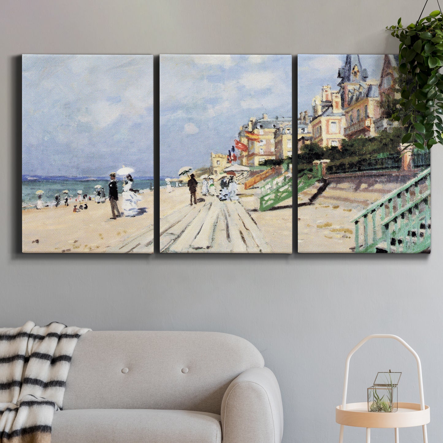 Three-panel canvas wall art featuring figures strolling along beach, displayed in a modern living room above a sofa.