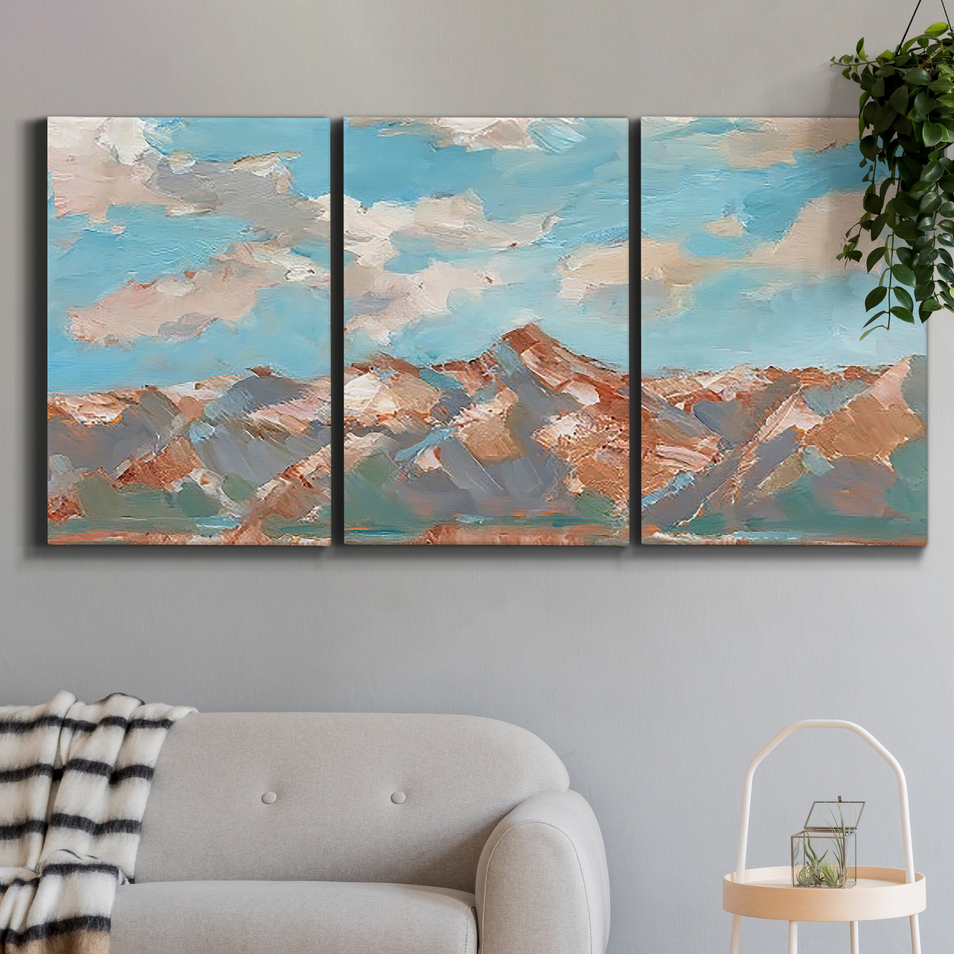 Three-panel canvas wall art featuring soft pastel western hills landscape, displayed in a modern living room above a sofa.