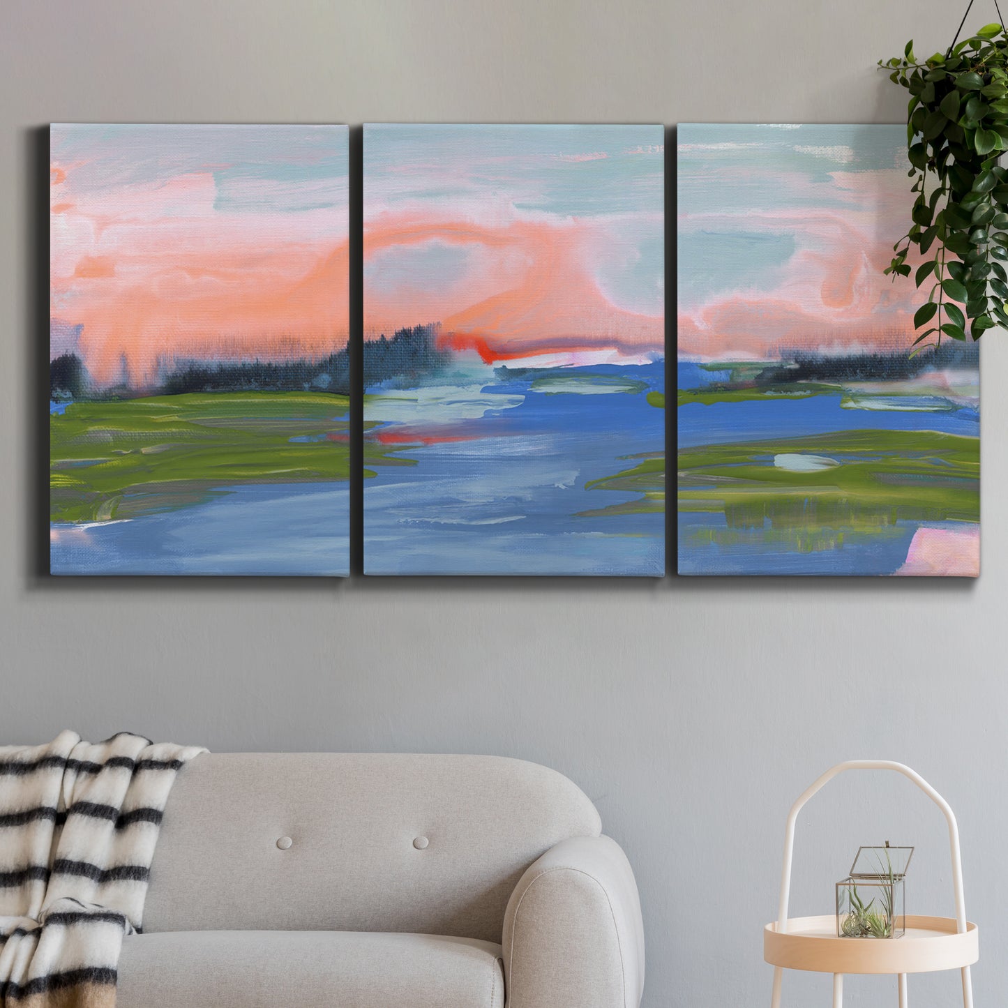 Three-panel canvas wall art featuring sunset reflections across calm sea, displayed in a modern living room above a sofa.