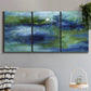 Three-panel canvas wall art featuring flowing blue abstract watercolor, displayed in a modern living room above a sofa.