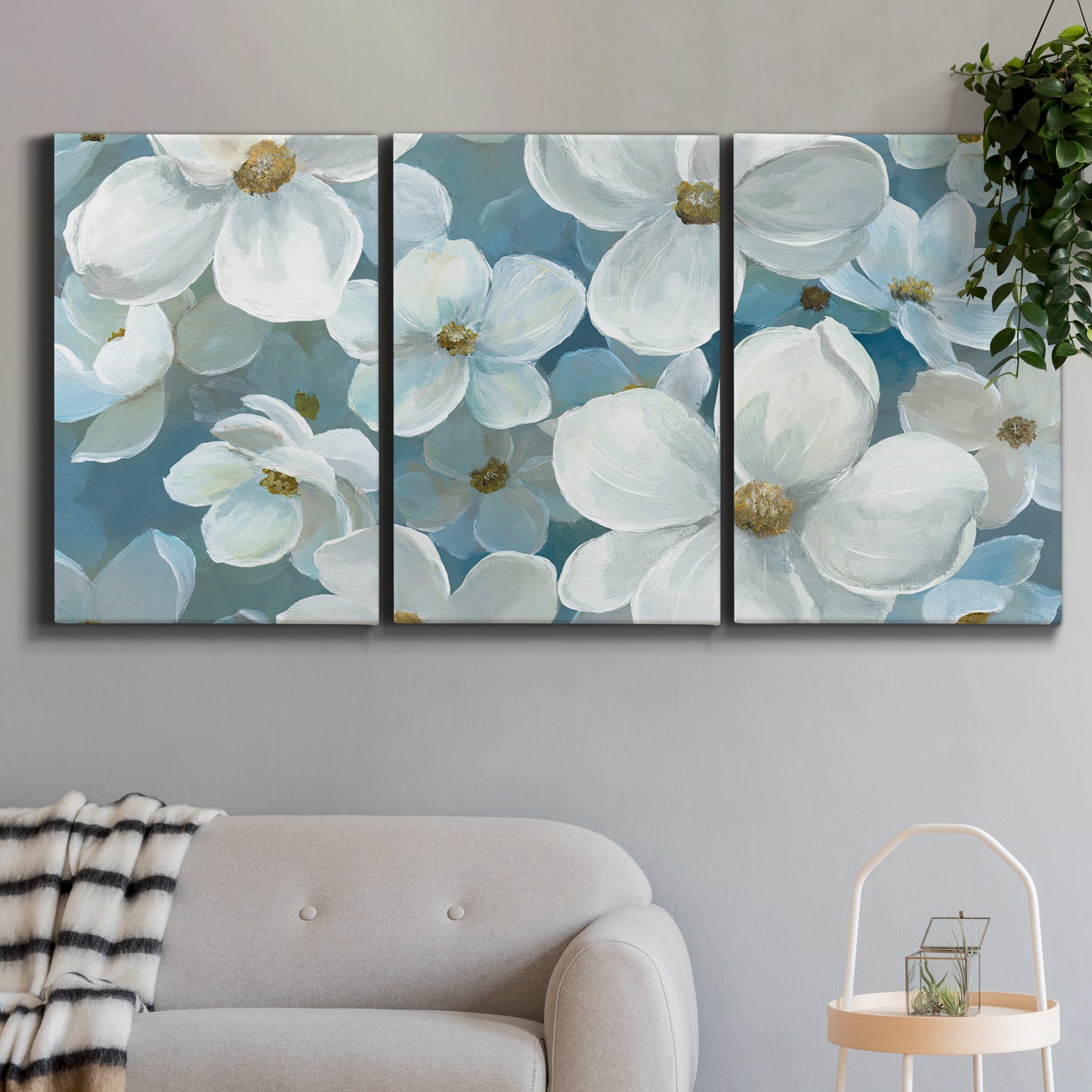 Three-panel canvas wall art featuring soft white floral abstraction, displayed in a modern living room above a sofa.
