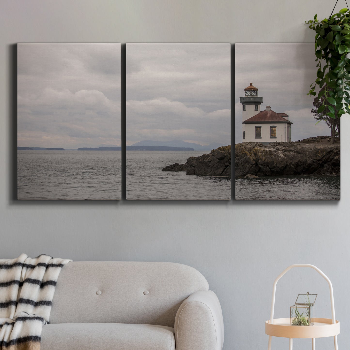 Three-panel canvas wall art featuring lighthouse watching over coastline, displayed in a modern living room above a sofa.