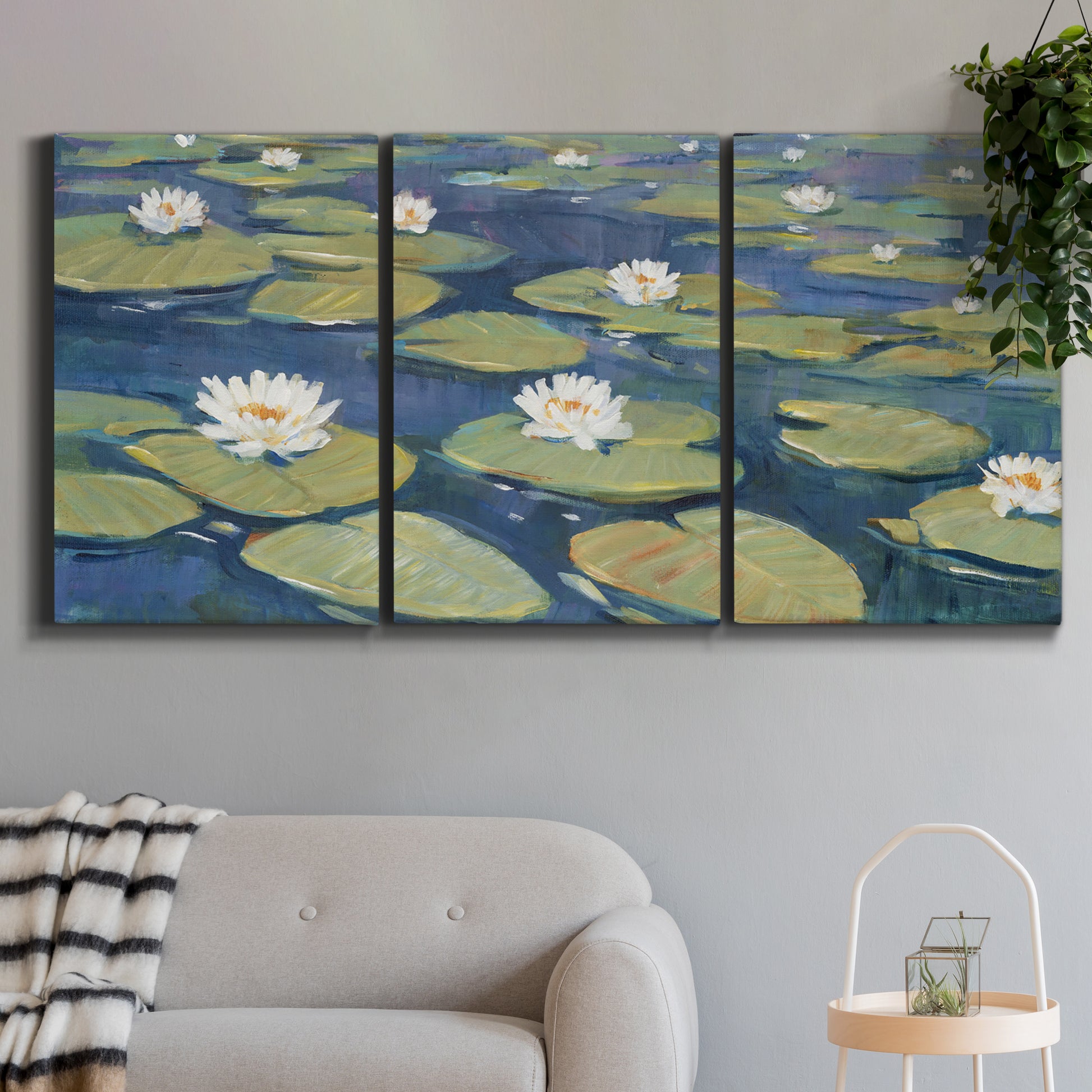 Three-panel canvas wall art featuring water lilies floating on pond, displayed in a modern living room above a sofa.