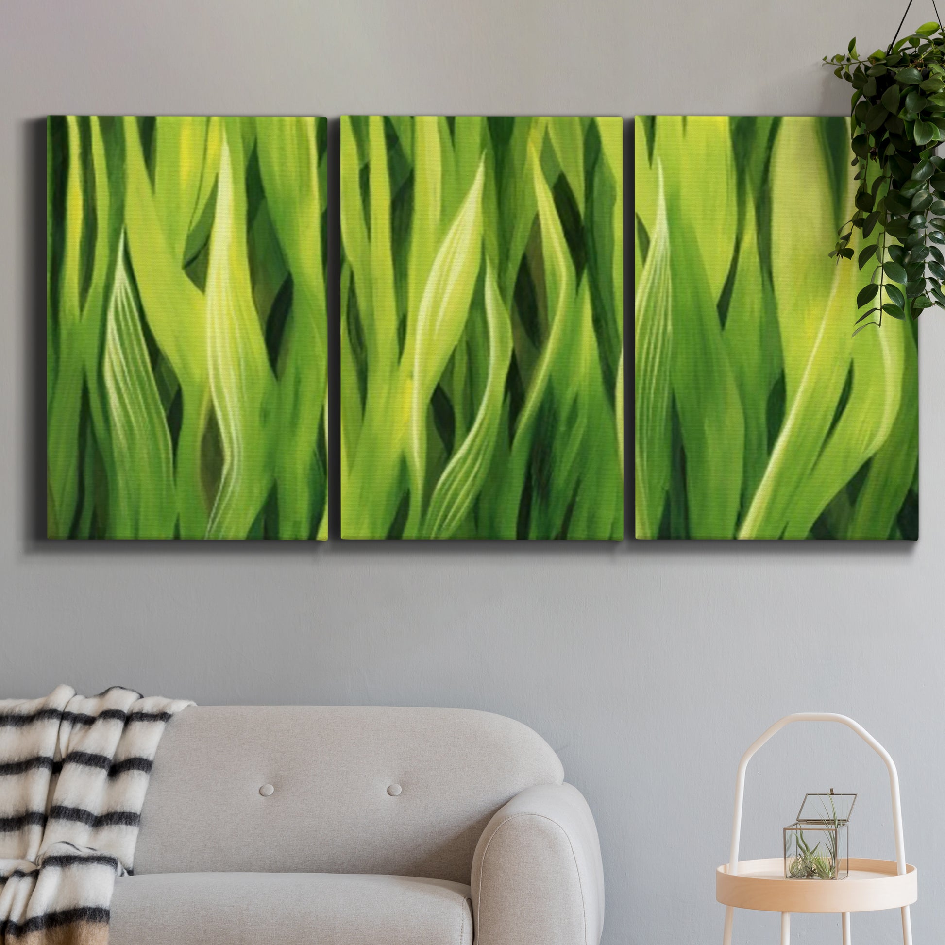 Three-panel canvas wall art featuring close view of tall green grass blades, displayed in a modern living room above a sofa.