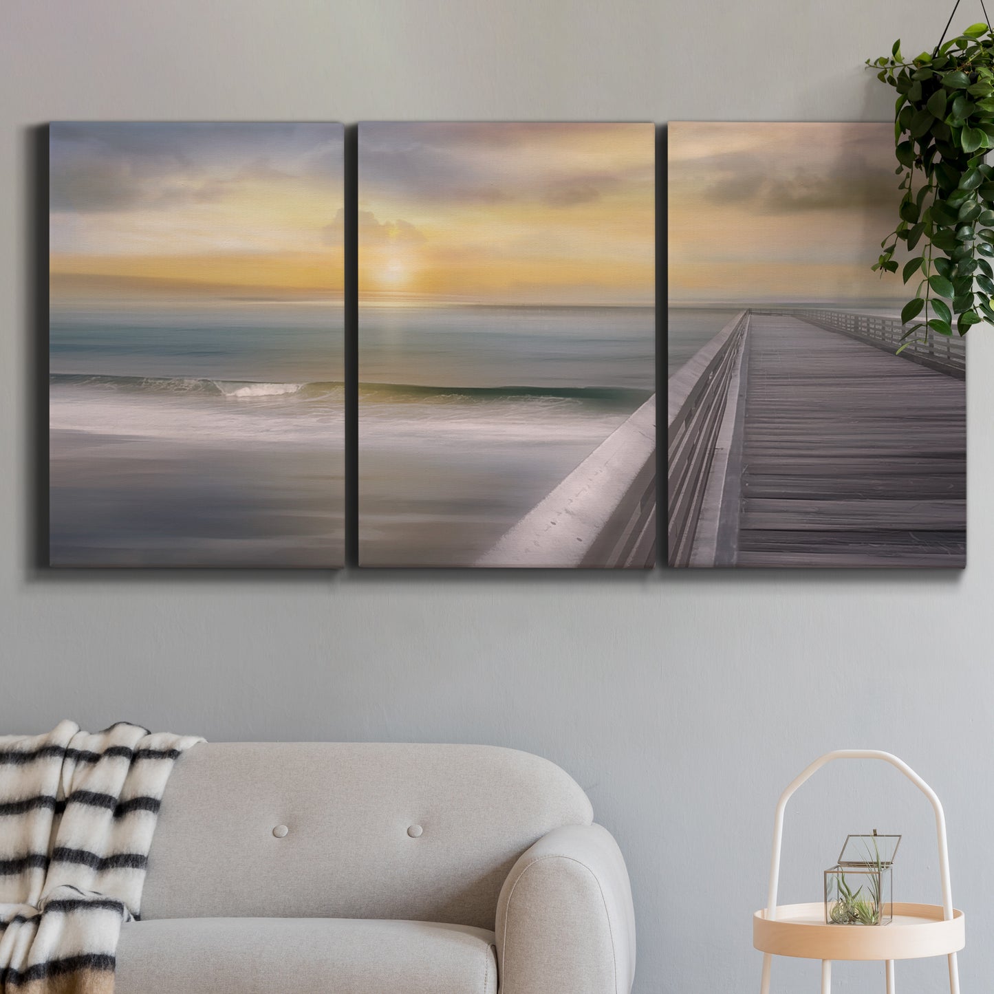 Three-panel canvas wall art featuring tropical beach at sunset photograph, displayed in a modern living room above a sofa.