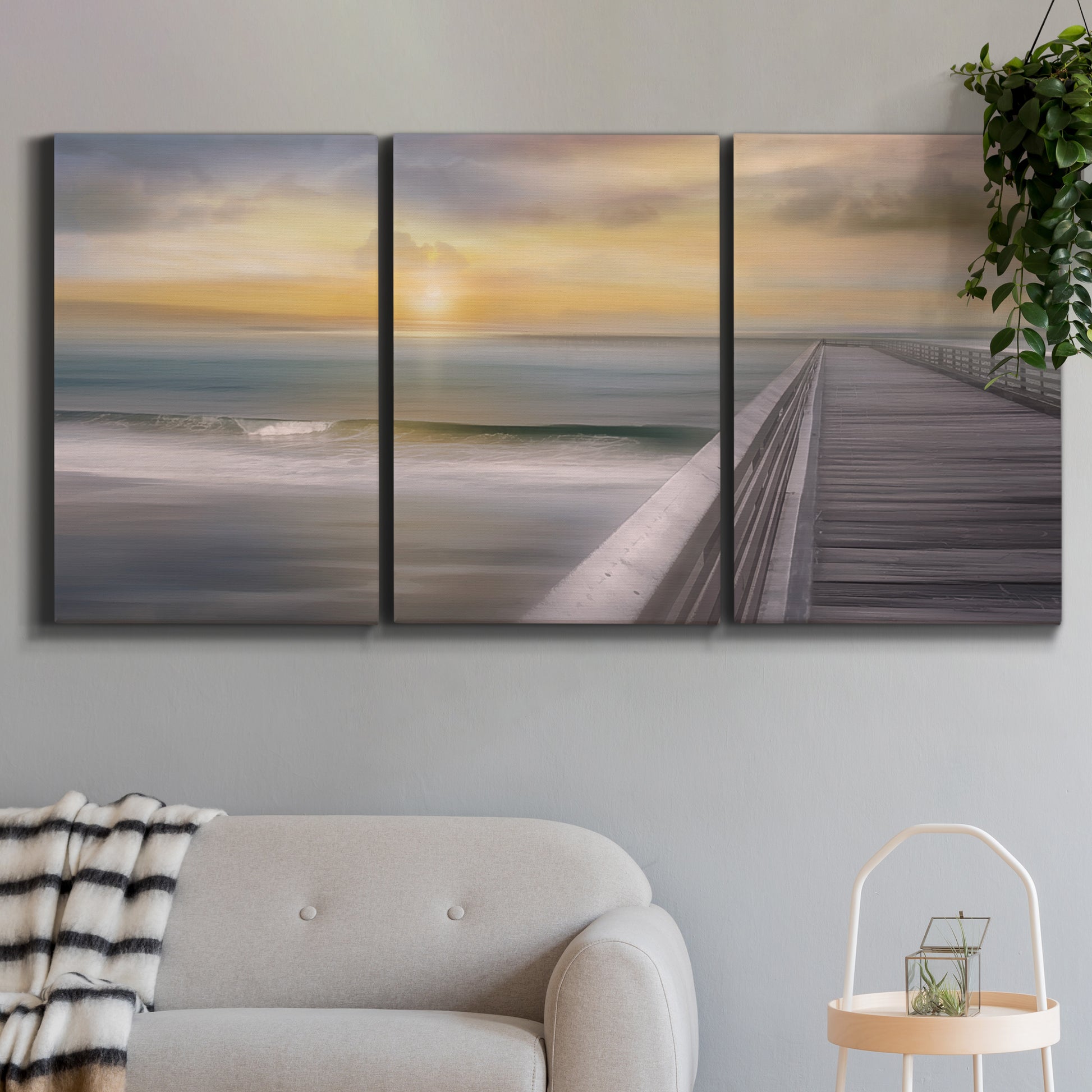 Three-panel canvas wall art featuring tropical beach at sunset photograph, displayed in a modern living room above a sofa.