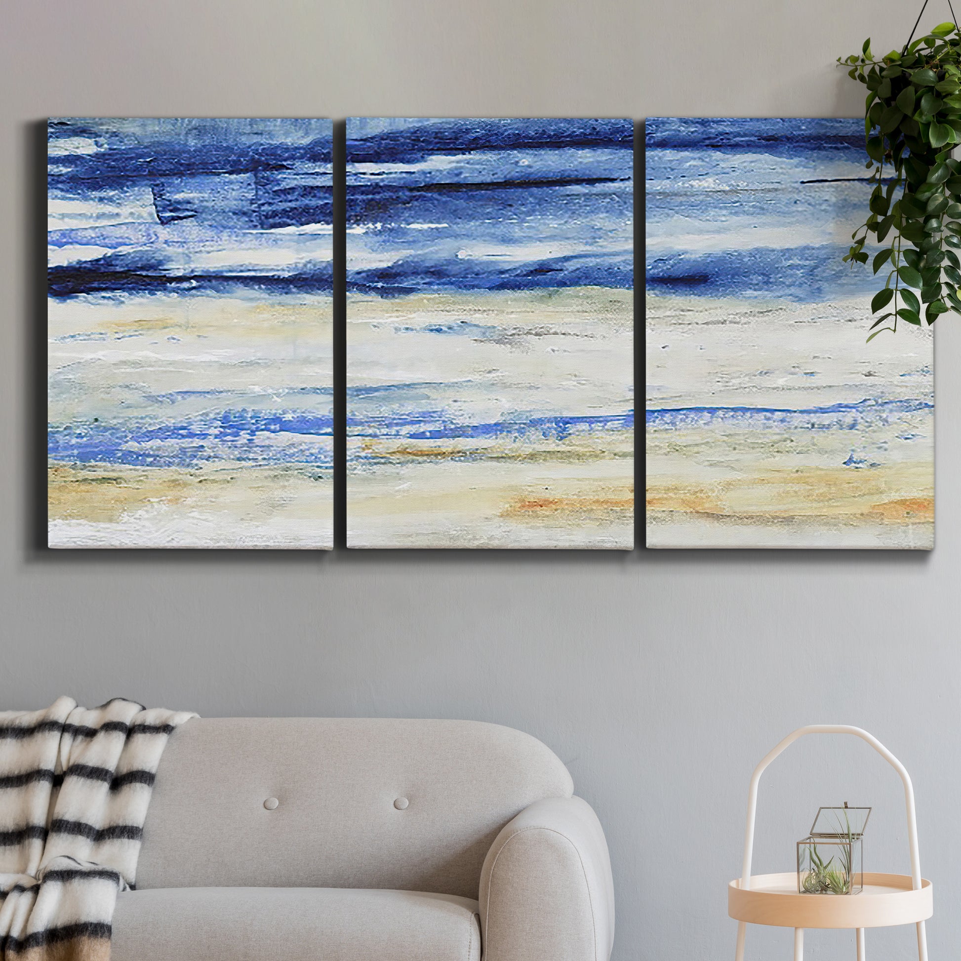 Three-panel canvas wall art featuring turbulent abstract ocean wave motion, displayed in a modern living room above a sofa.