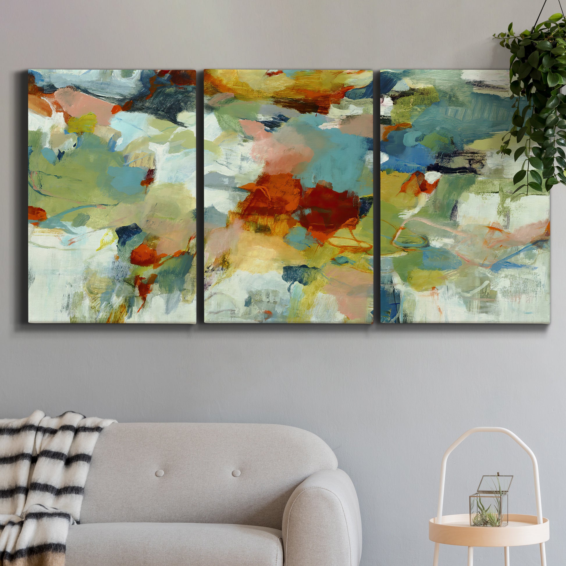 Three-panel canvas wall art featuring celebratory abstract color movement, displayed in a modern living room above a sofa.