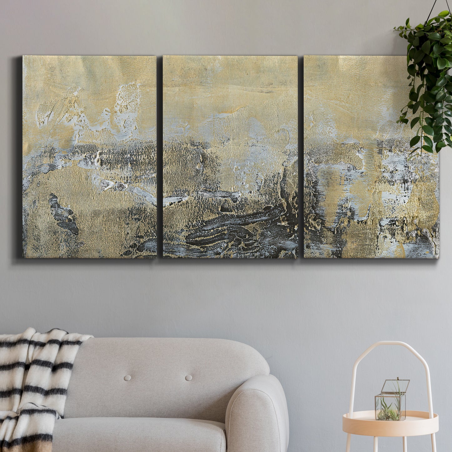 Three-panel canvas wall art featuring gold toned abstract horizon, displayed in a modern living room above a sofa.