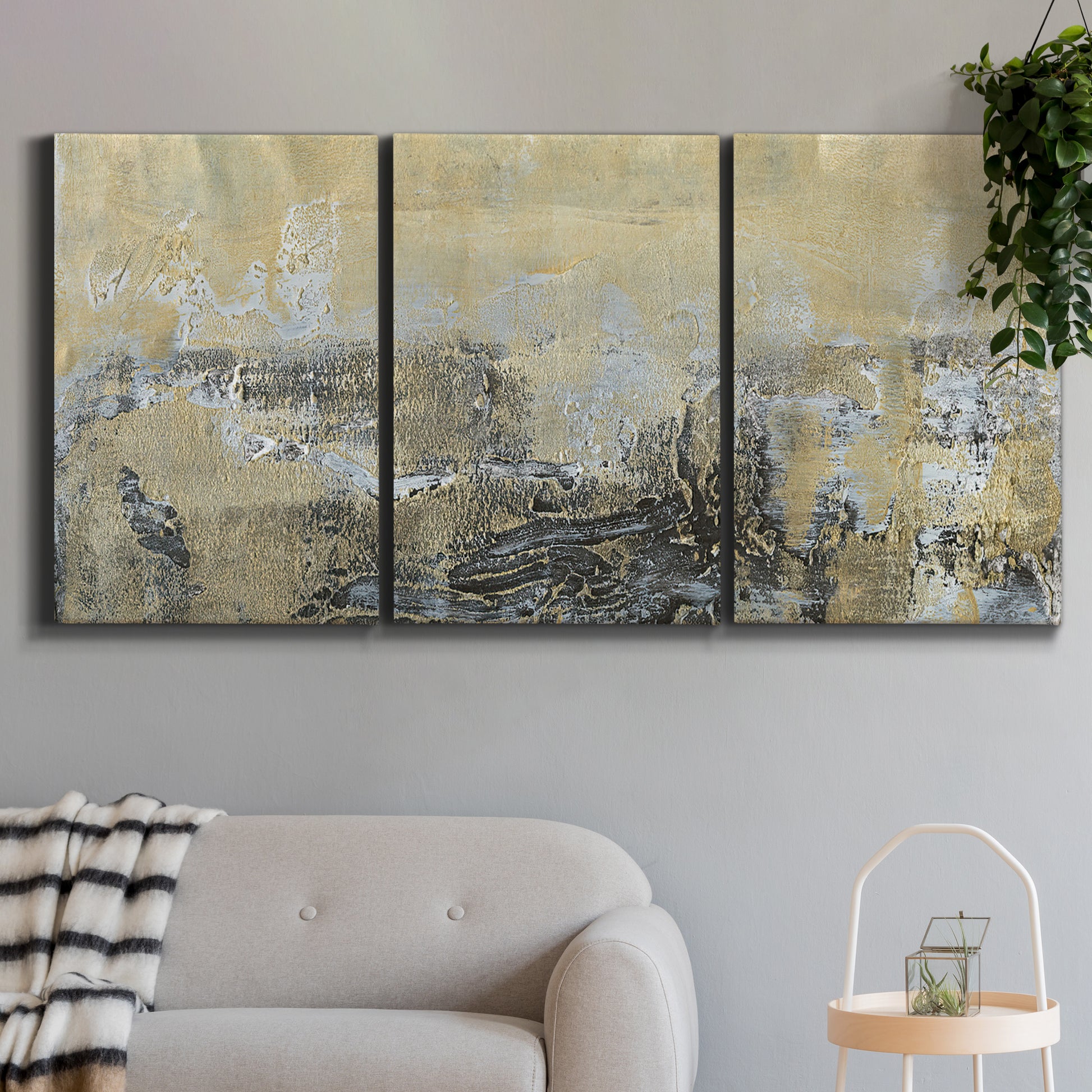 Three-panel canvas wall art featuring gold toned abstract horizon, displayed in a modern living room above a sofa.