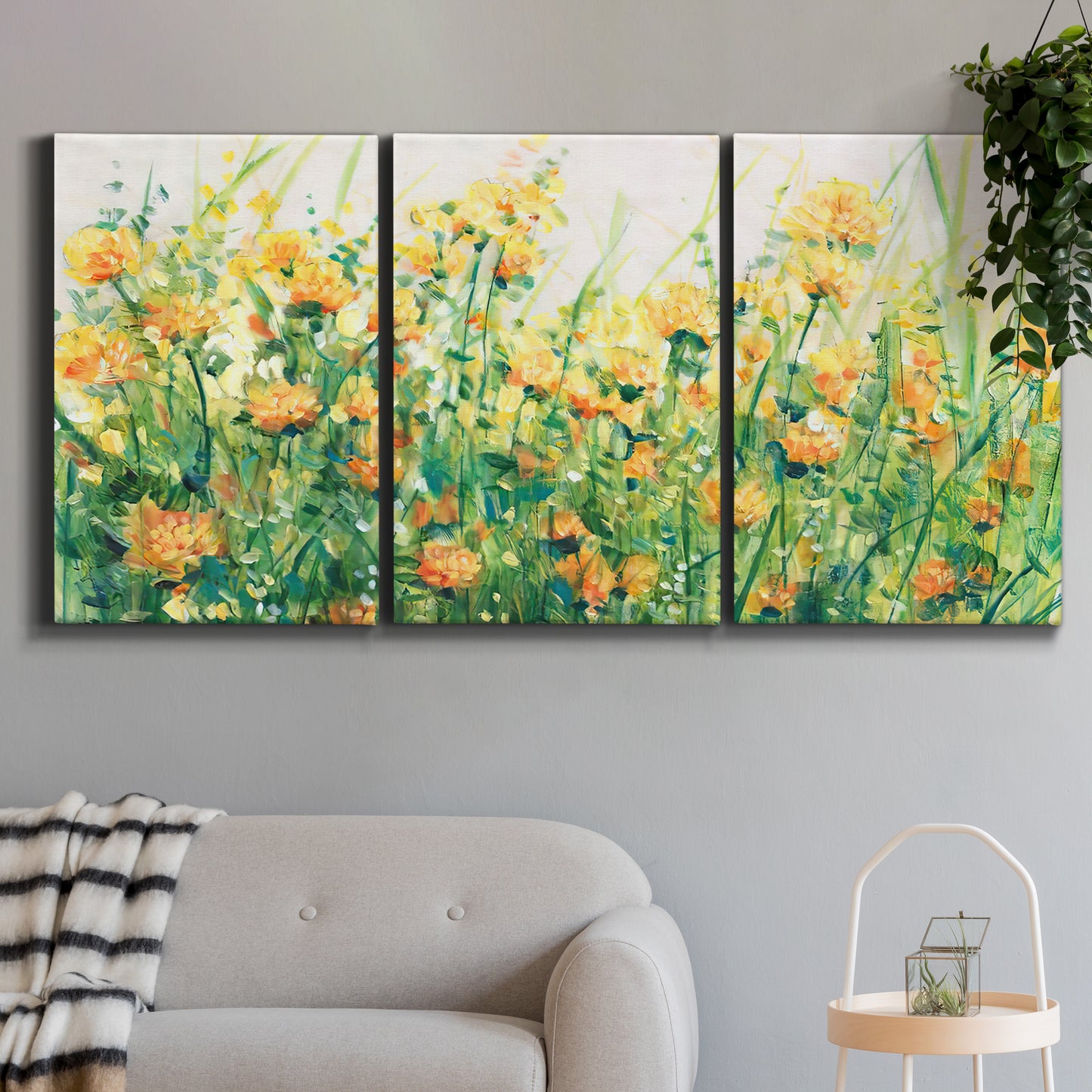Three-panel canvas wall art featuring colorful garden flowers in bloom, displayed in a modern living room above a sofa.