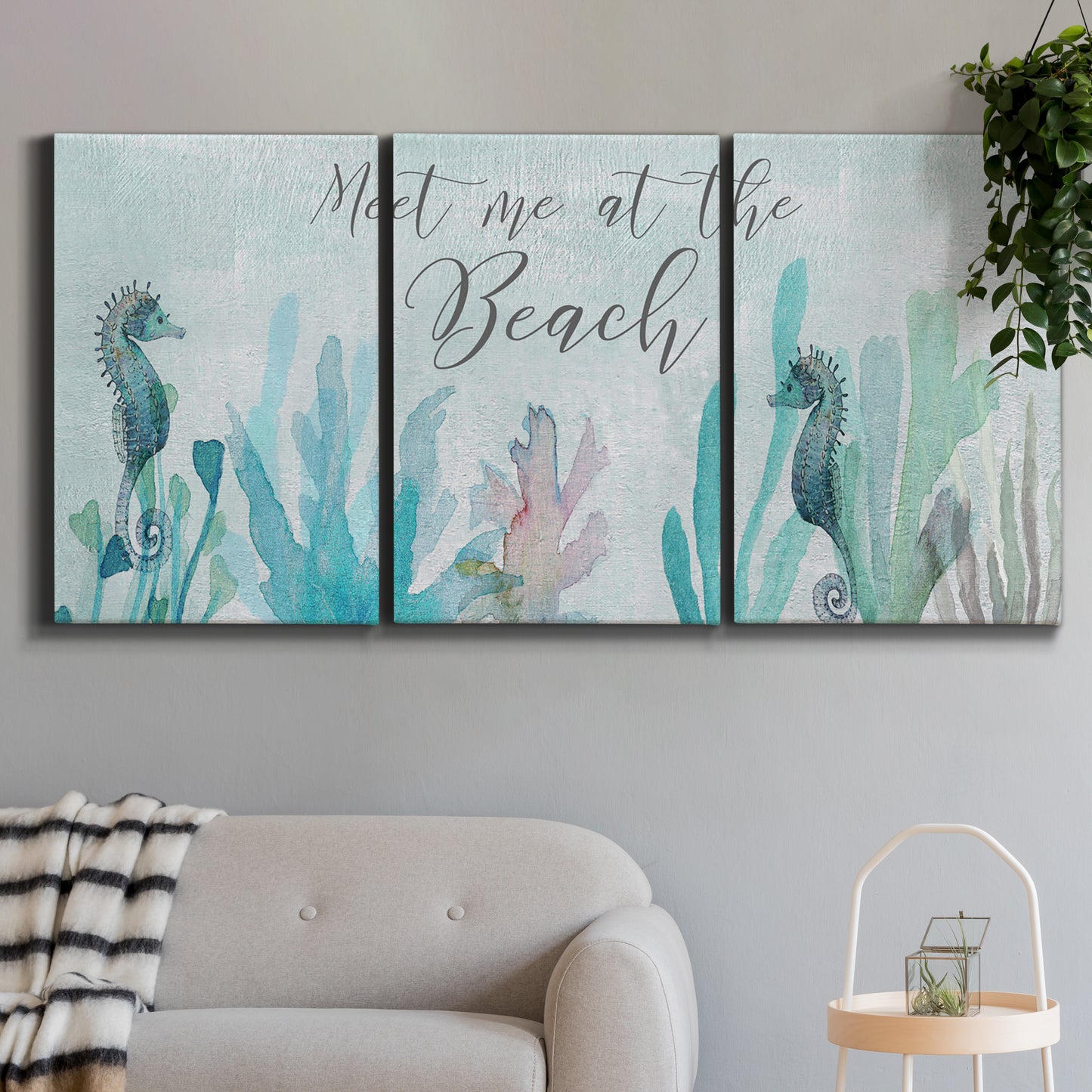 Three-panel canvas wall art featuring coastal typography with seahorses, displayed in a modern living room above a sofa.