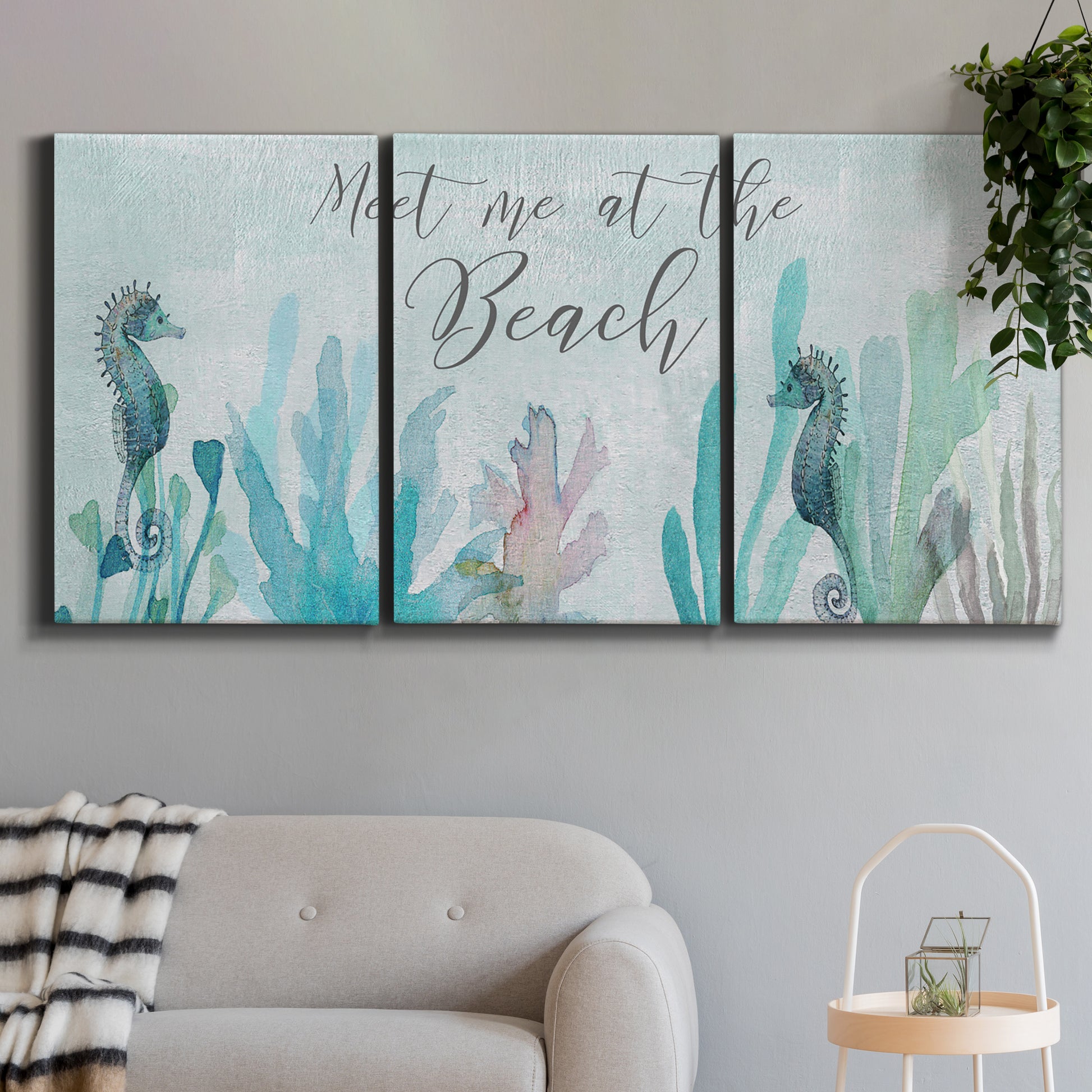 Three-panel canvas wall art featuring coastal typography with seahorses, displayed in a modern living room above a sofa.