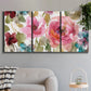 Three-panel canvas wall art featuring colorful floral watercolor composition, displayed in a modern living room above a sofa.