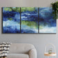 Three-panel canvas wall art featuring flowing blue abstract watercolor, displayed in a modern living room above a sofa.