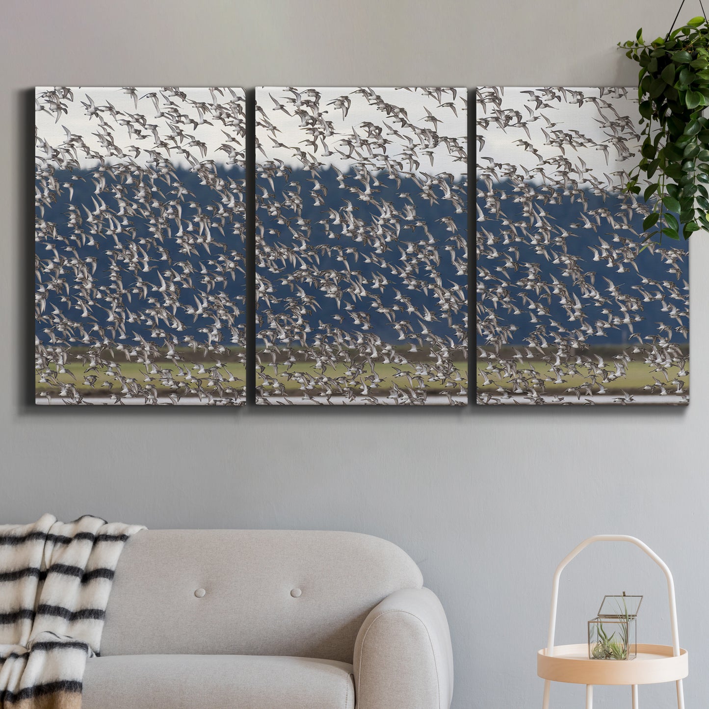 Three-panel canvas wall art featuring group of animals in open field, displayed in a modern living room above a sofa.