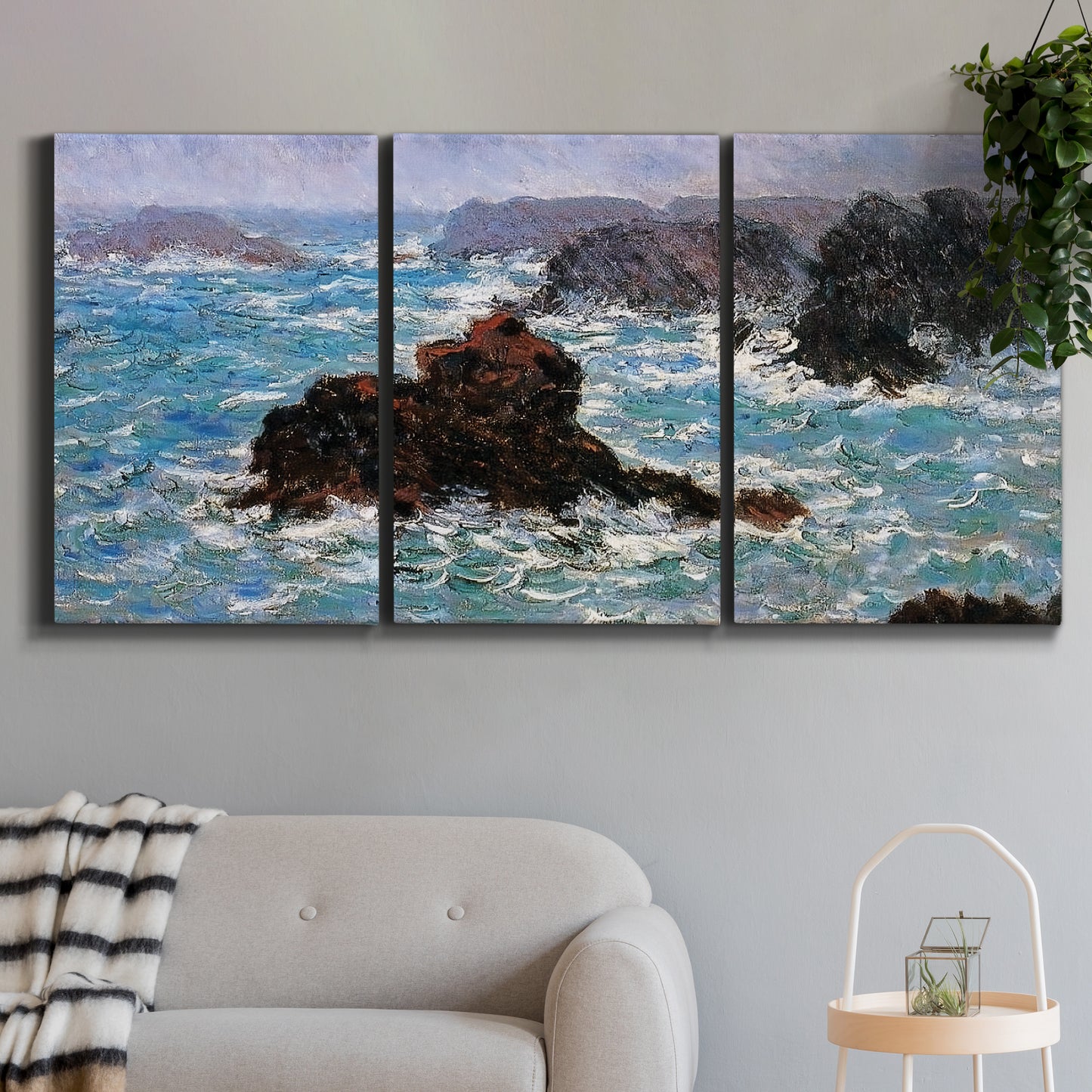 Three-panel canvas wall art featuring storm waves battering rocky coast, displayed in a modern living room above a sofa.