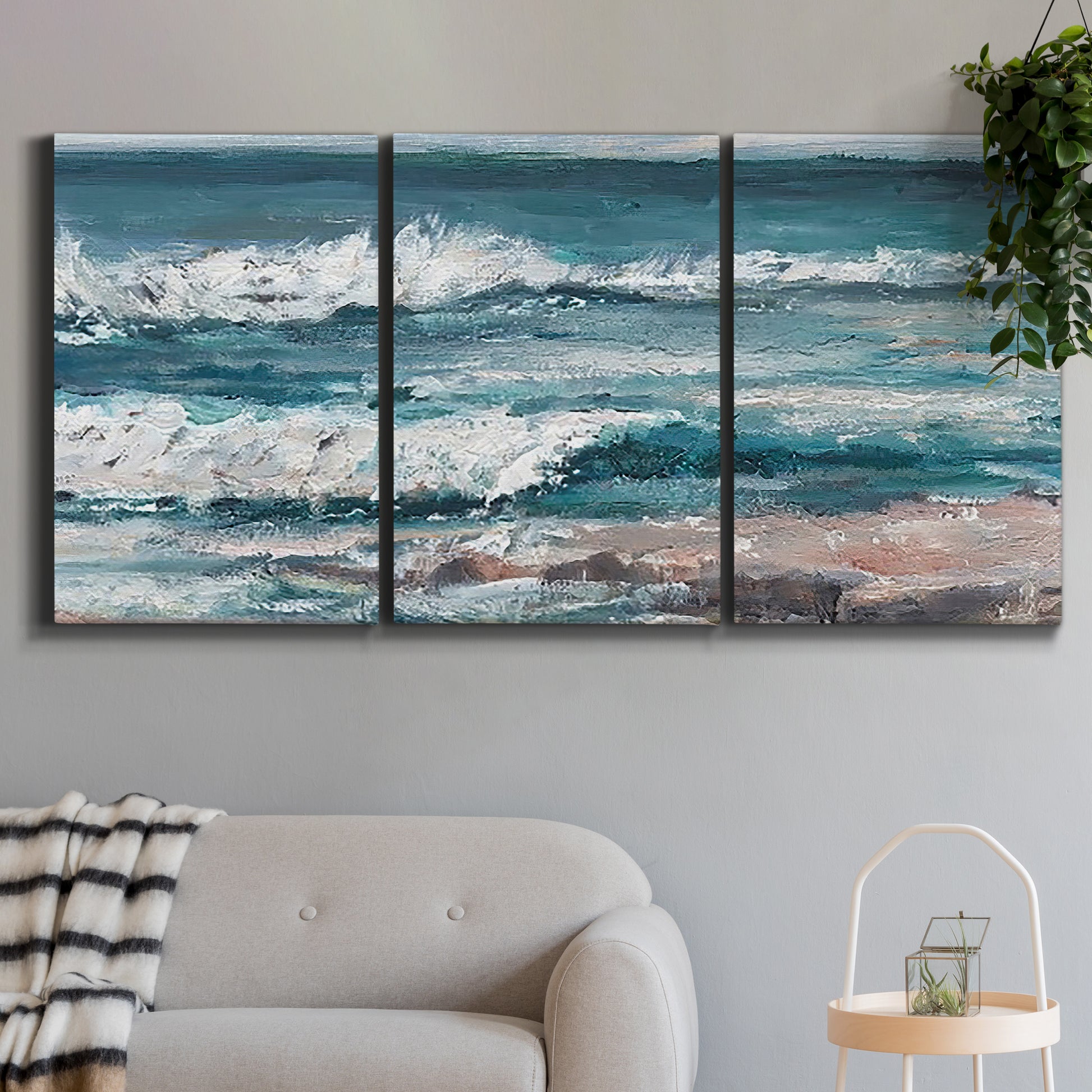 Three-panel canvas wall art featuring crashing ocean waves along shoreline, displayed in a modern living room above a sofa.