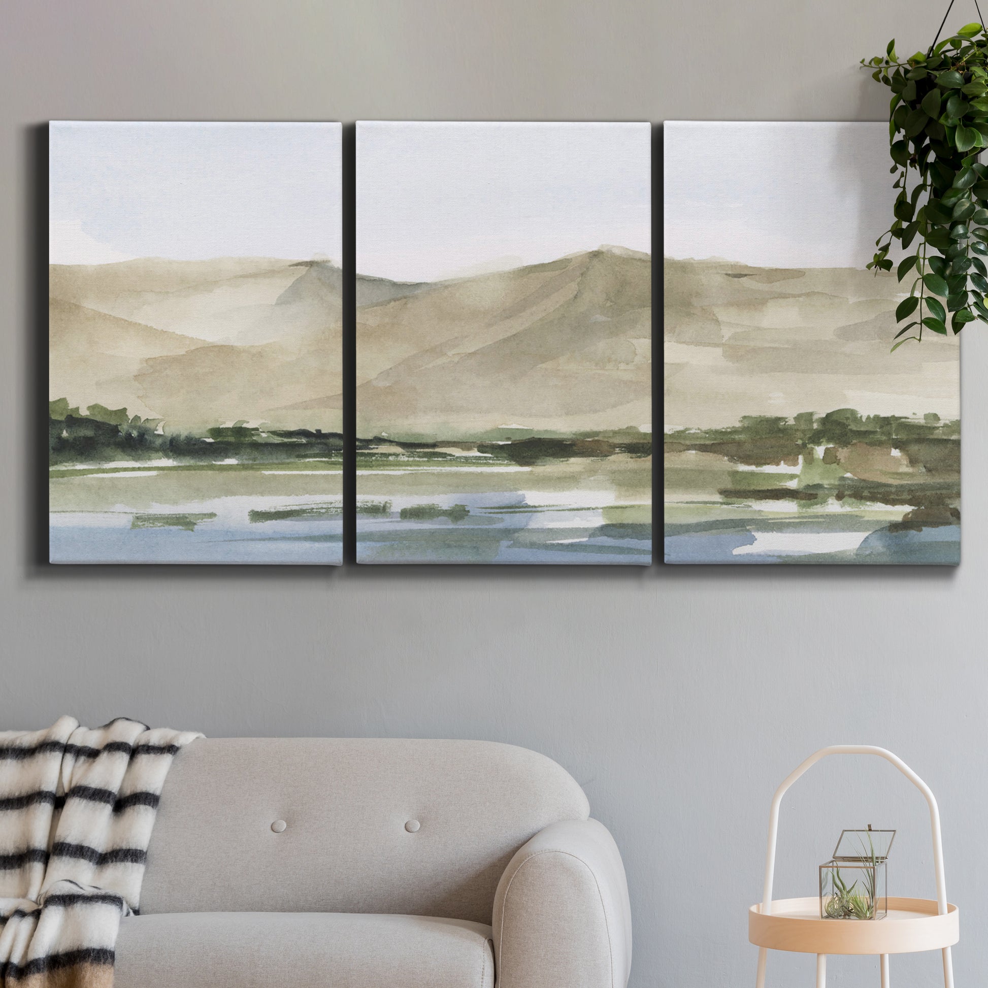Three-panel canvas wall art featuring desert mountain landscape watercolor, displayed in a modern living room above a sofa.