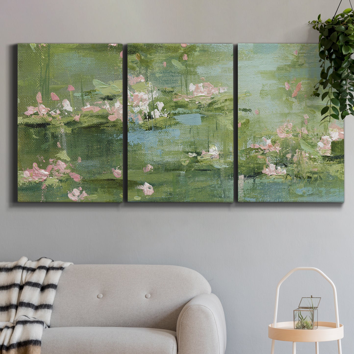 Three-panel canvas wall art featuring soft green water lilies, displayed in a modern living room above a sofa.