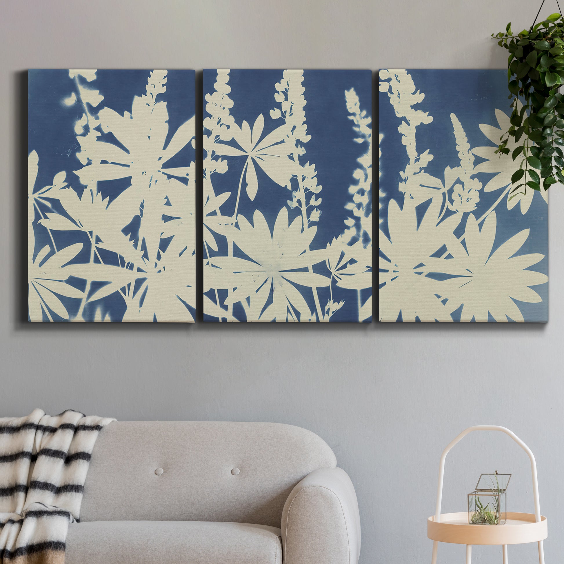 Three-panel canvas wall art featuring delicate lupine floral composition, displayed in a modern living room above a sofa.