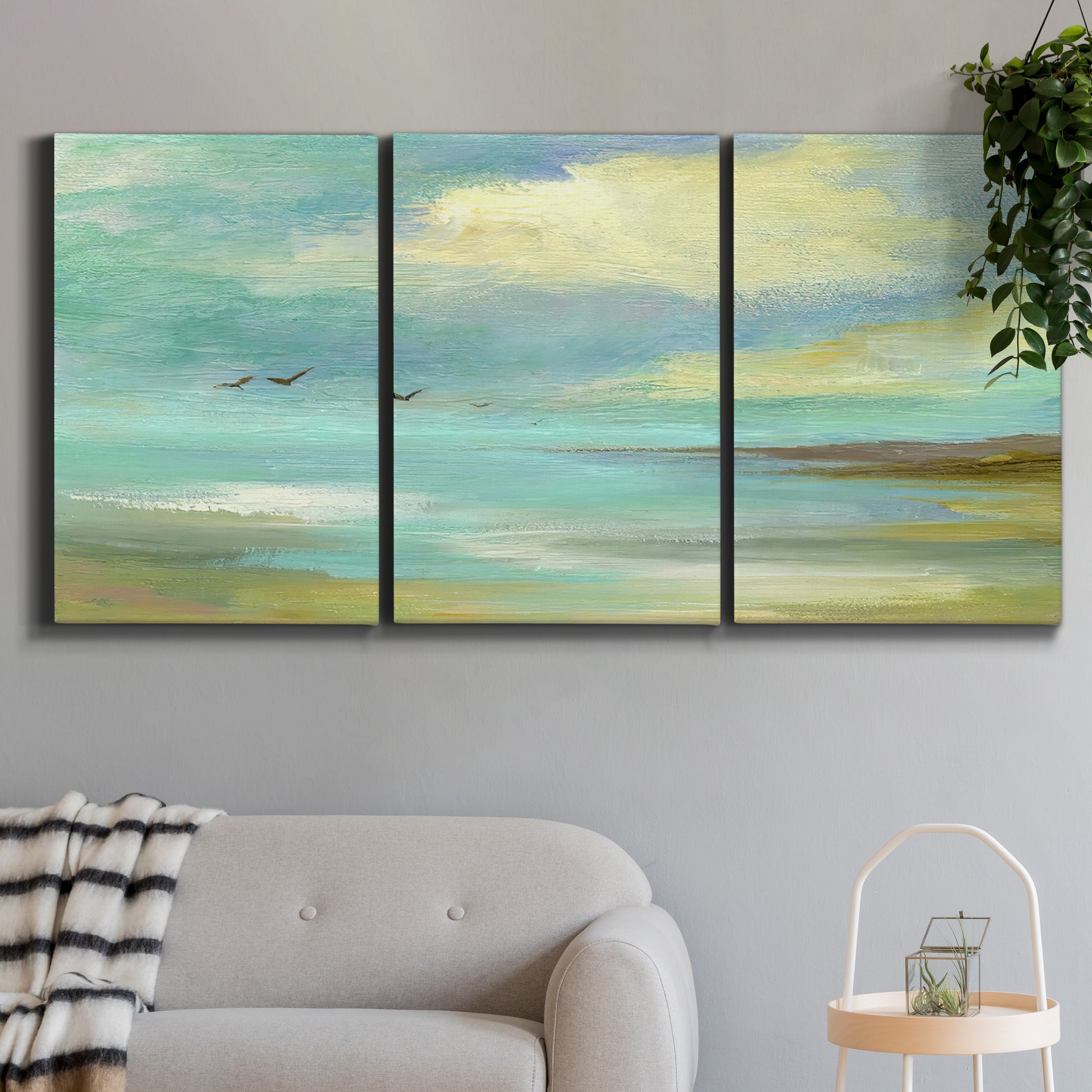 Three-panel canvas wall art featuring calm coastal drift patterns, displayed in a modern living room above a sofa.