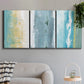Three-panel canvas wall art featuring abstract coastal shoreline textures, displayed in a modern living room above a sofa.