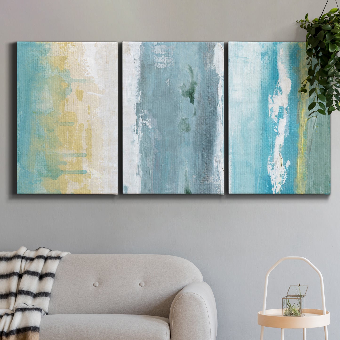 Three-panel canvas wall art featuring abstract coastal shoreline textures, displayed in a modern living room above a sofa.