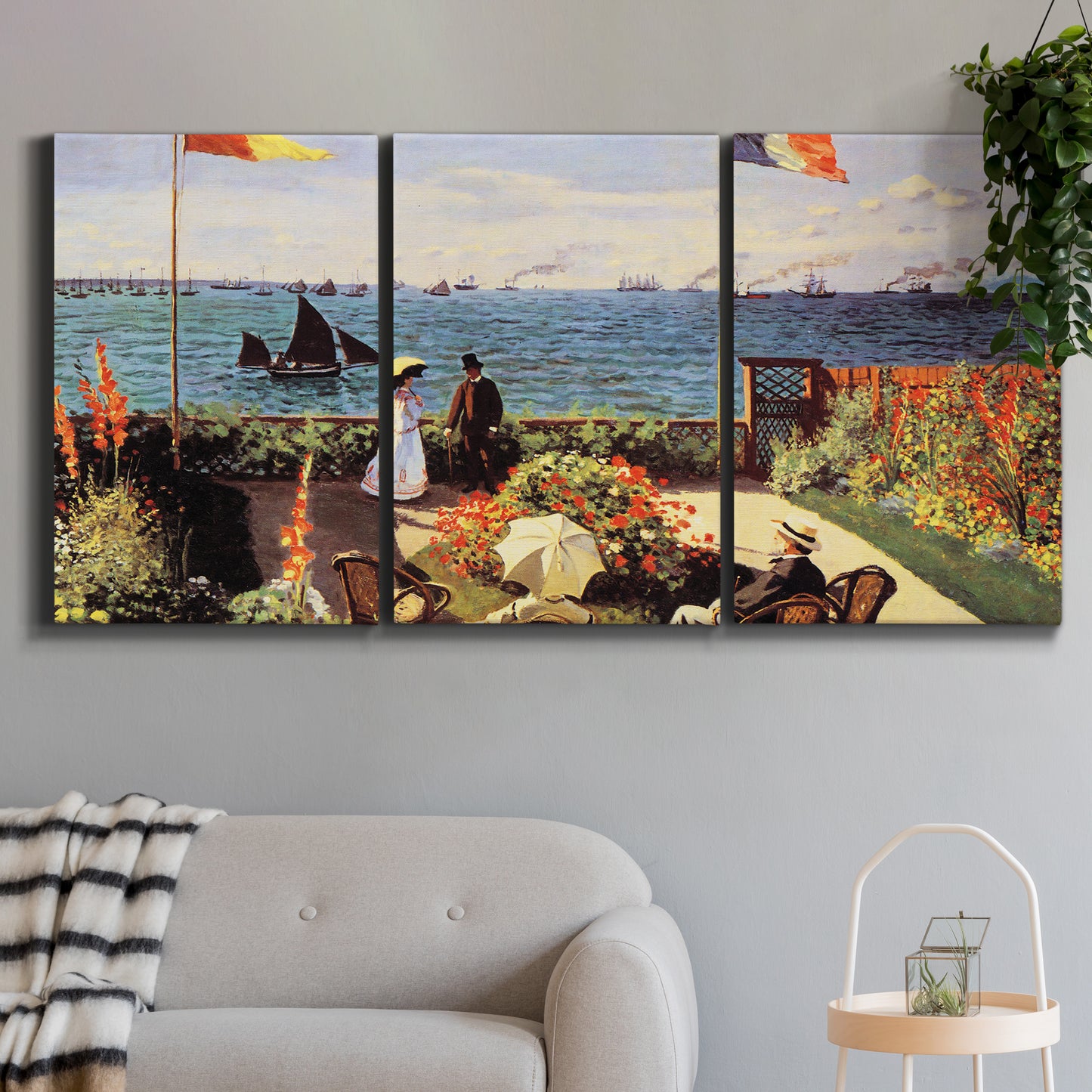 Three-panel canvas wall art featuring coastal garden overlooking sea, displayed in a modern living room above a sofa.