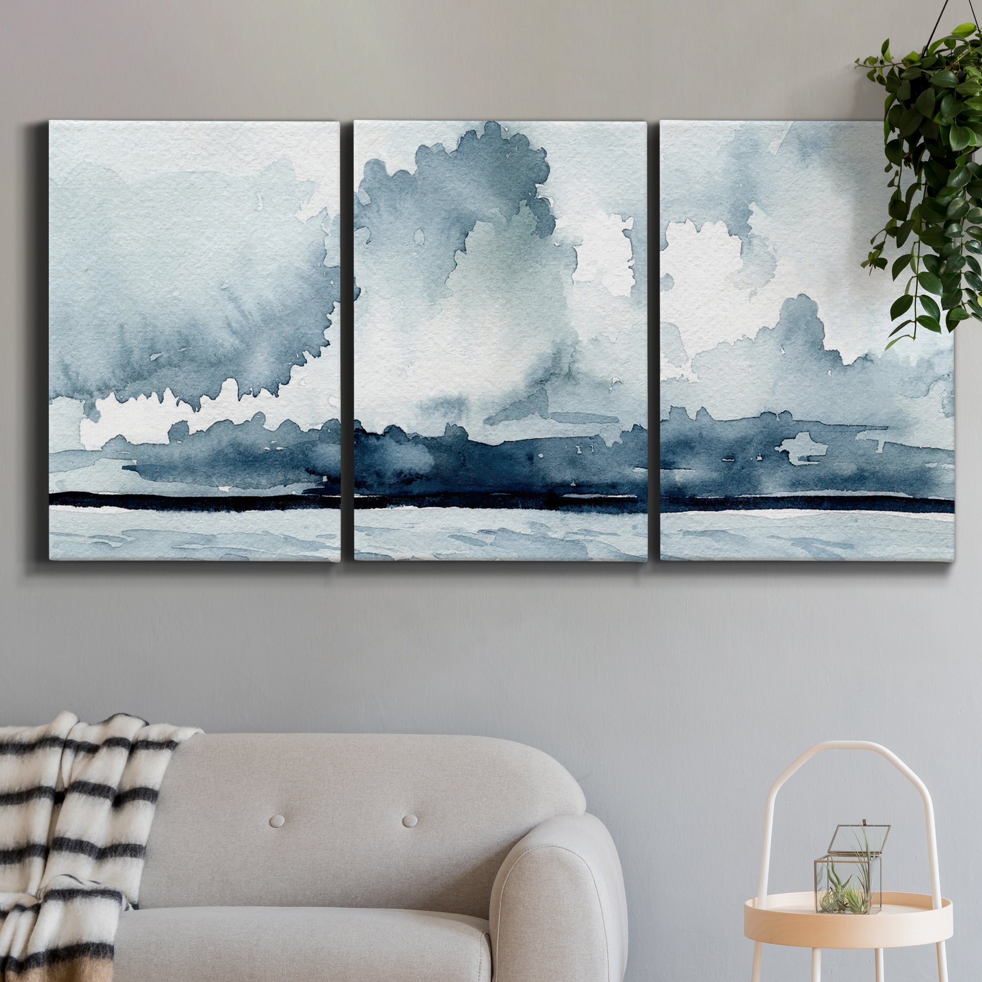 Three-panel canvas wall art featuring abstract rainstorm watercolor, displayed in a modern living room above a sofa.