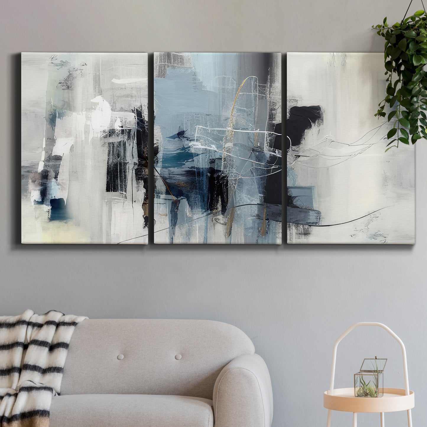 Three-panel canvas wall art featuring cool abstract winter color wash, displayed in a modern living room above a sofa.