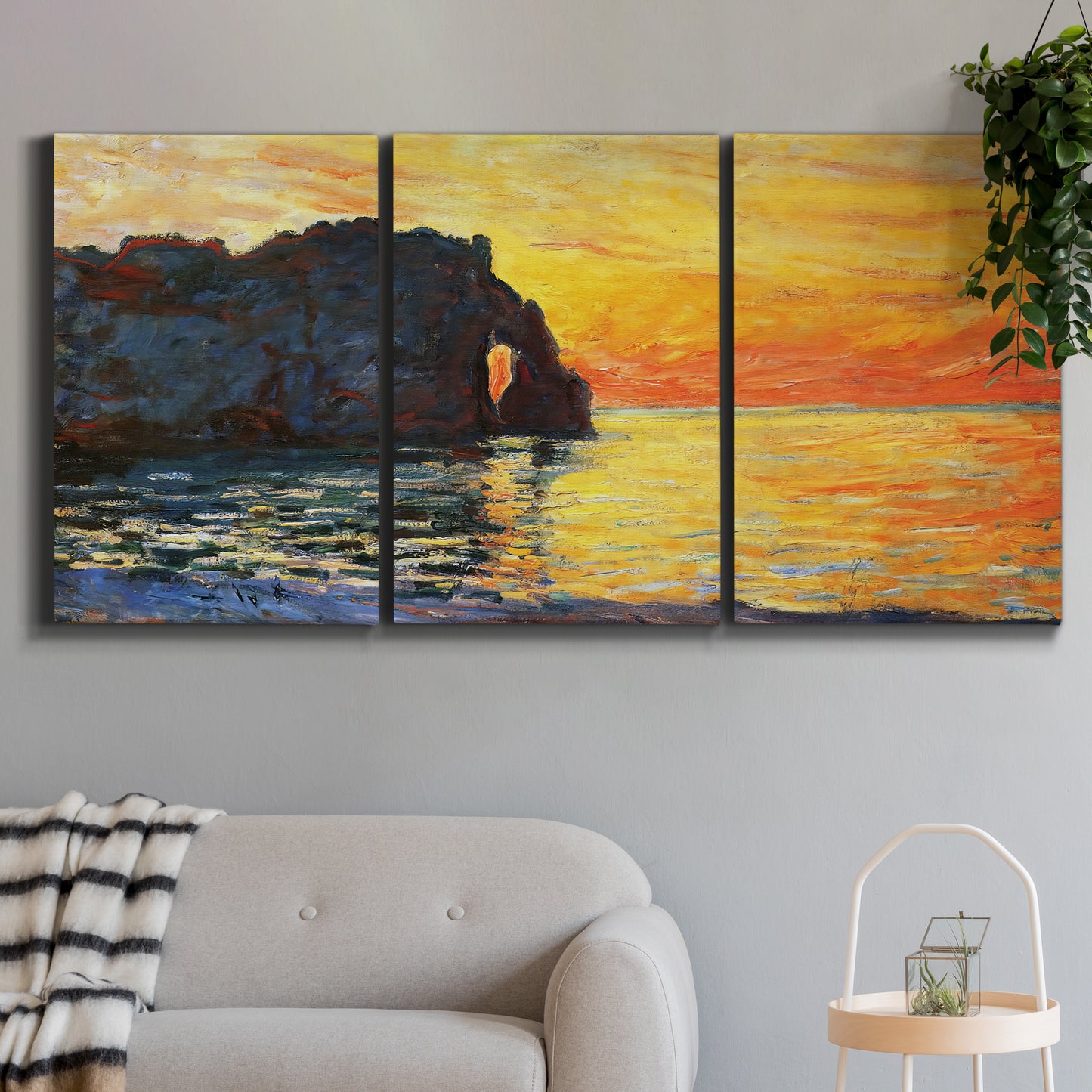 Three-panel canvas wall art featuring arched coastal cliff above sea, displayed in a modern living room above a sofa.