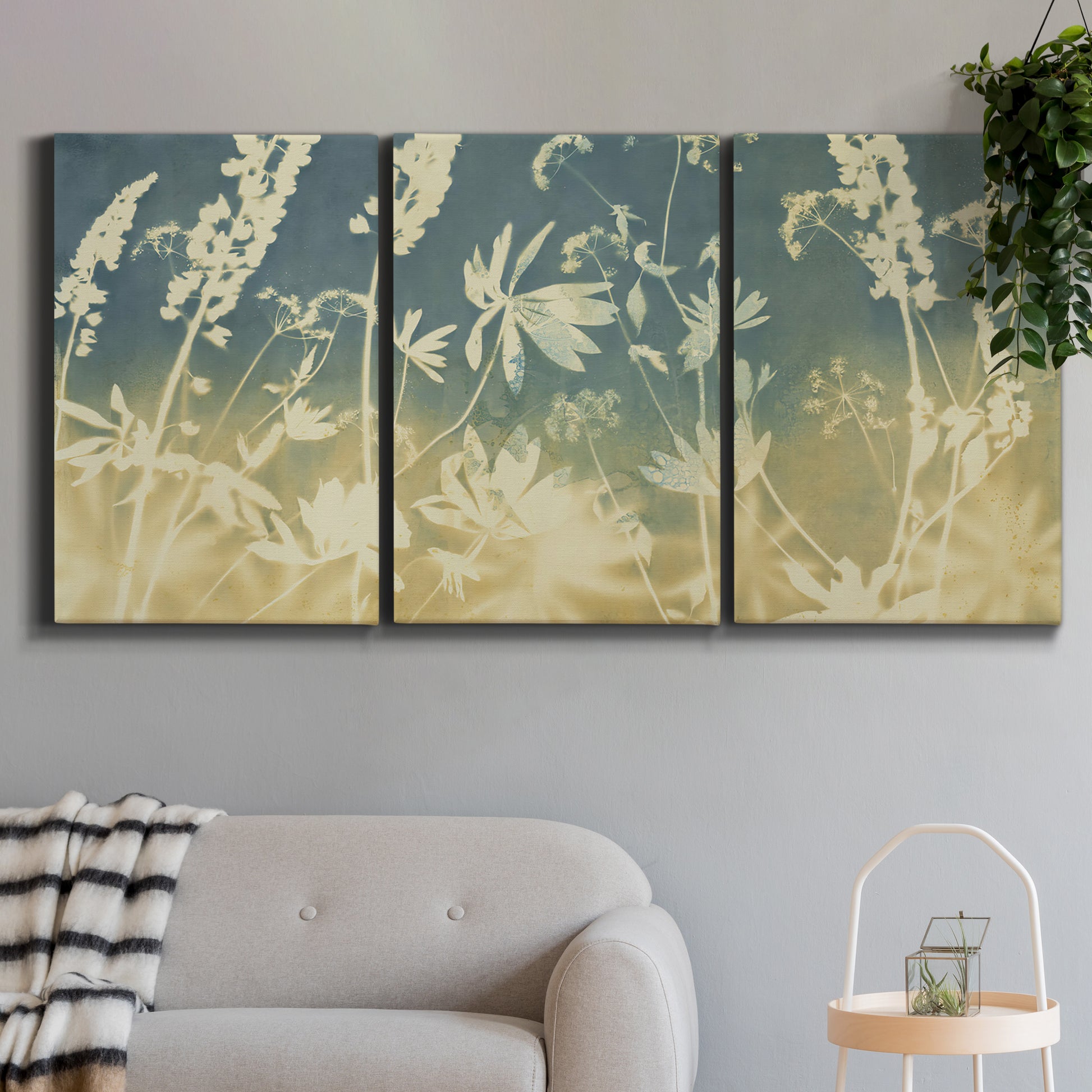 Three-panel canvas wall art featuring lupine flowers in seasonal bloom, displayed in a modern living room above a sofa.