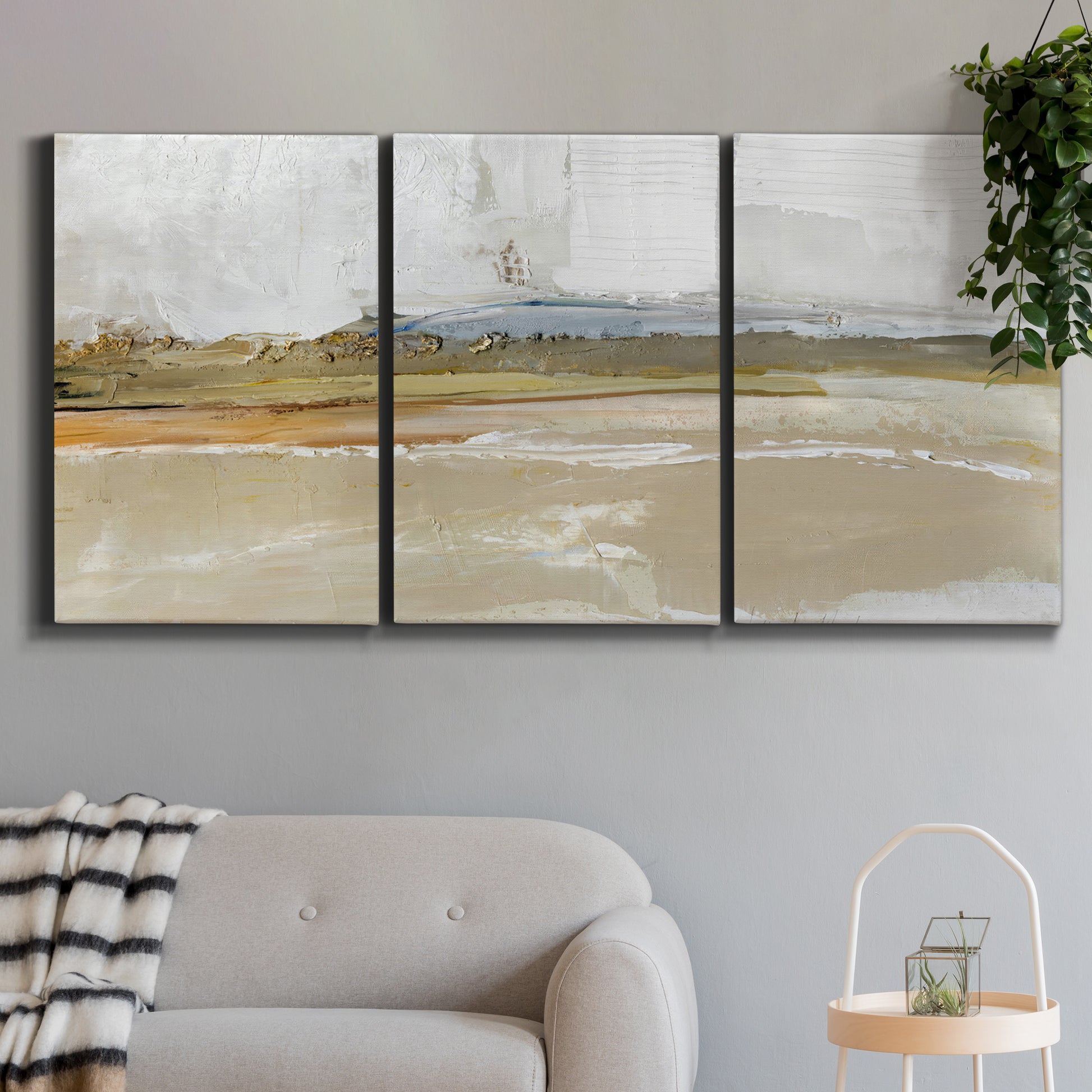 Three-panel canvas wall art featuring golden hour light over landscape, displayed in a modern living room above a sofa.