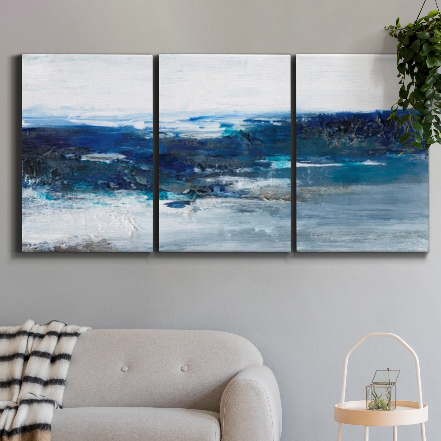 Three-panel canvas wall art featuring moody abstract sea with depth, displayed in a modern living room above a sofa.
