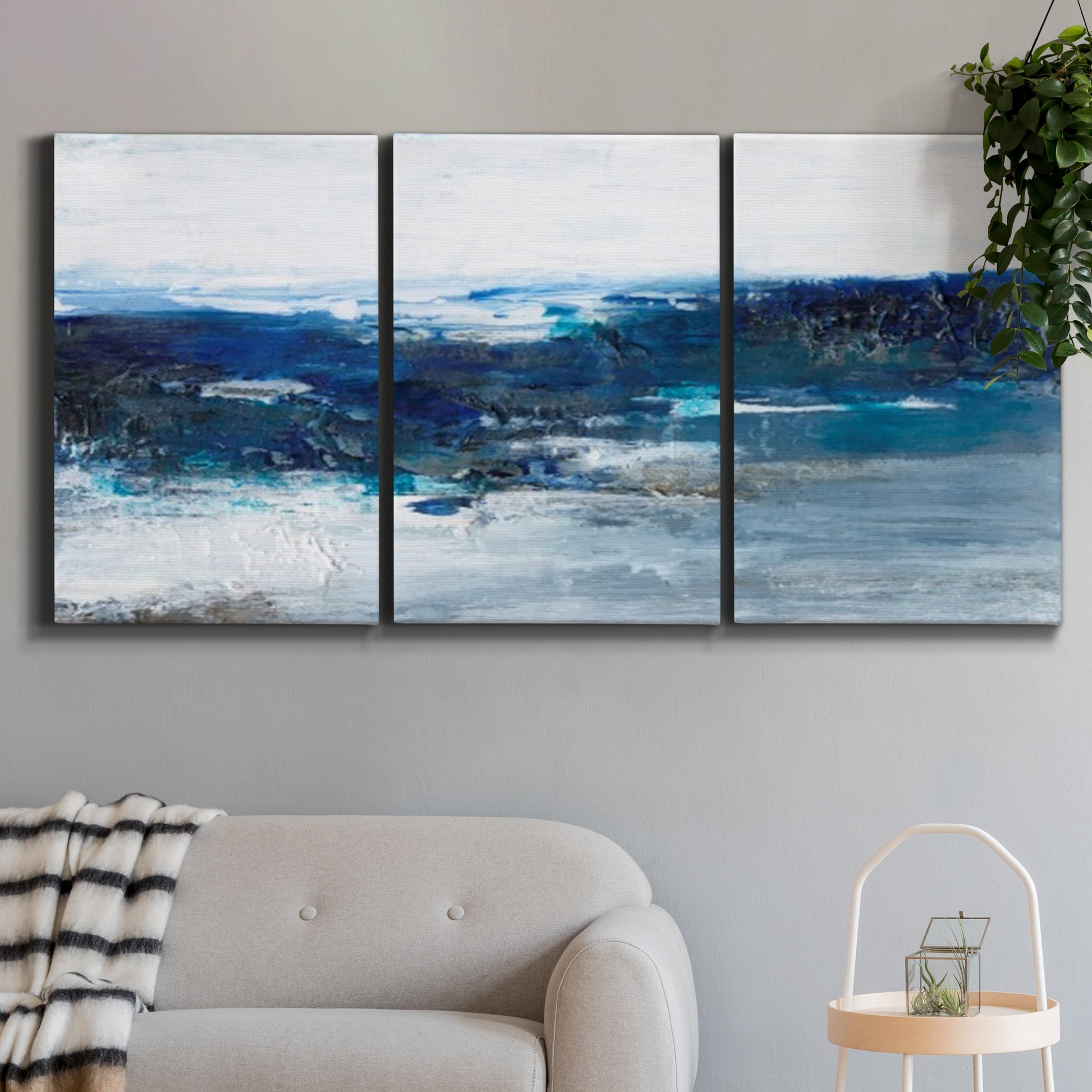 Three-panel canvas wall art featuring moody abstract sea with depth, displayed in a modern living room above a sofa.