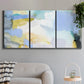 Three-panel canvas wall art featuring soft abstract spring watercolor tones, displayed in a modern living room above a sofa.