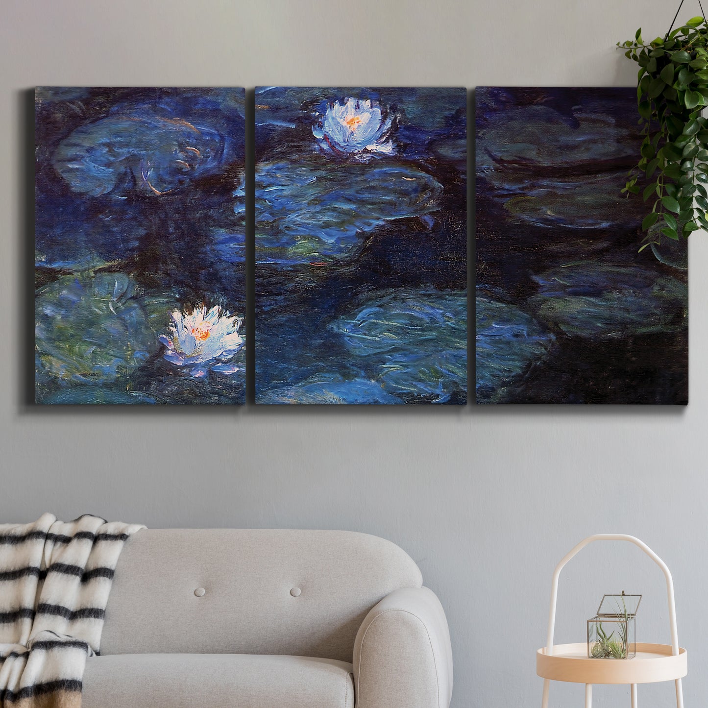 Three-panel canvas wall art featuring deep blue water lily reflections, displayed in a modern living room above a sofa.