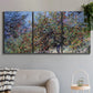 Three-panel canvas wall art featuring orchard of trees in spring bloom, displayed in a modern living room above a sofa.