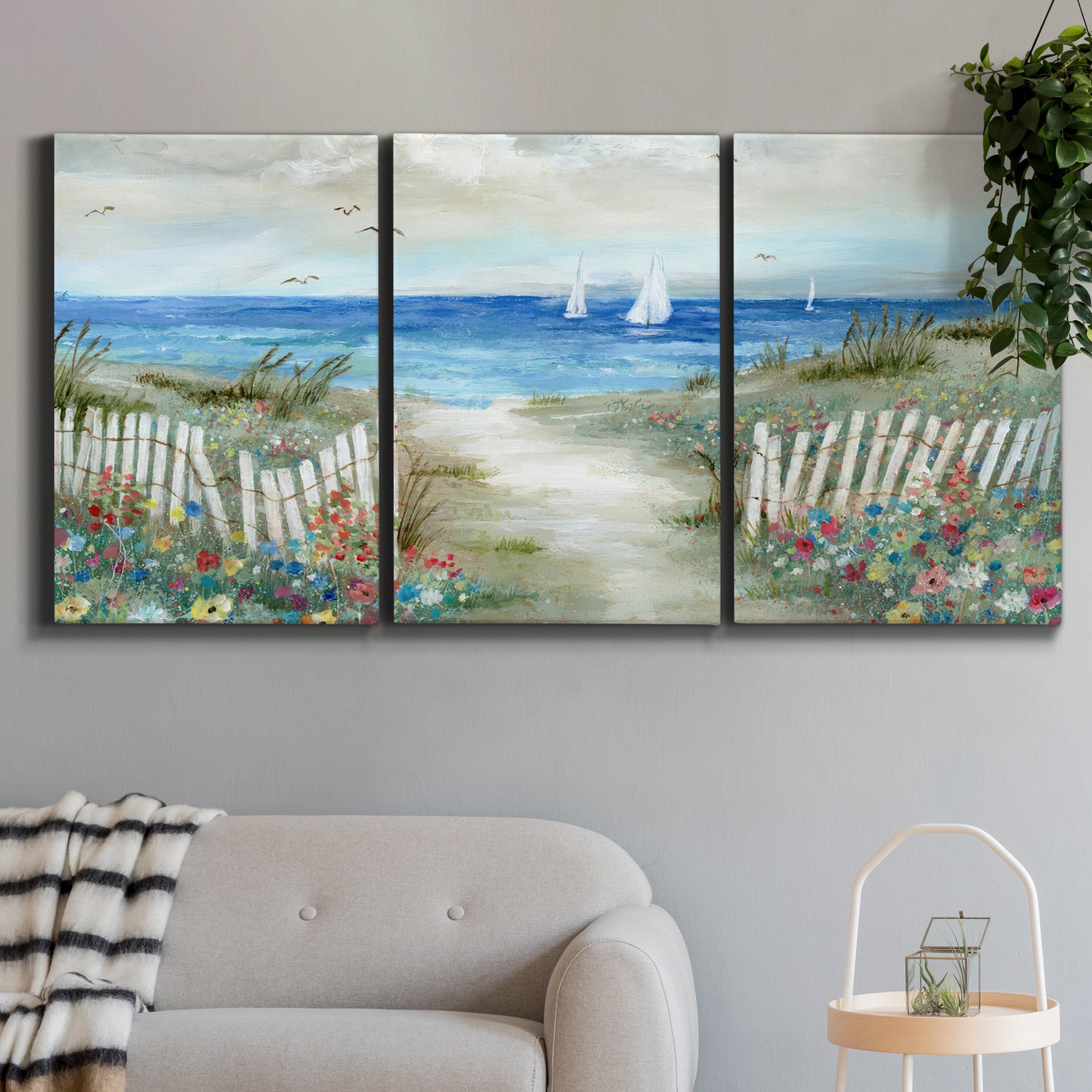 Three-panel canvas wall art featuring lush coastal garden landscape, displayed in a modern living room above a sofa.