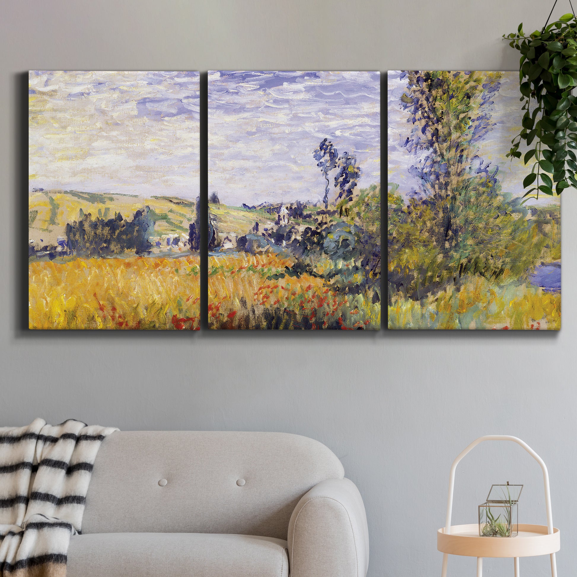 Three-panel canvas wall art featuring river village landscape with hills, displayed in a modern living room above a sofa.