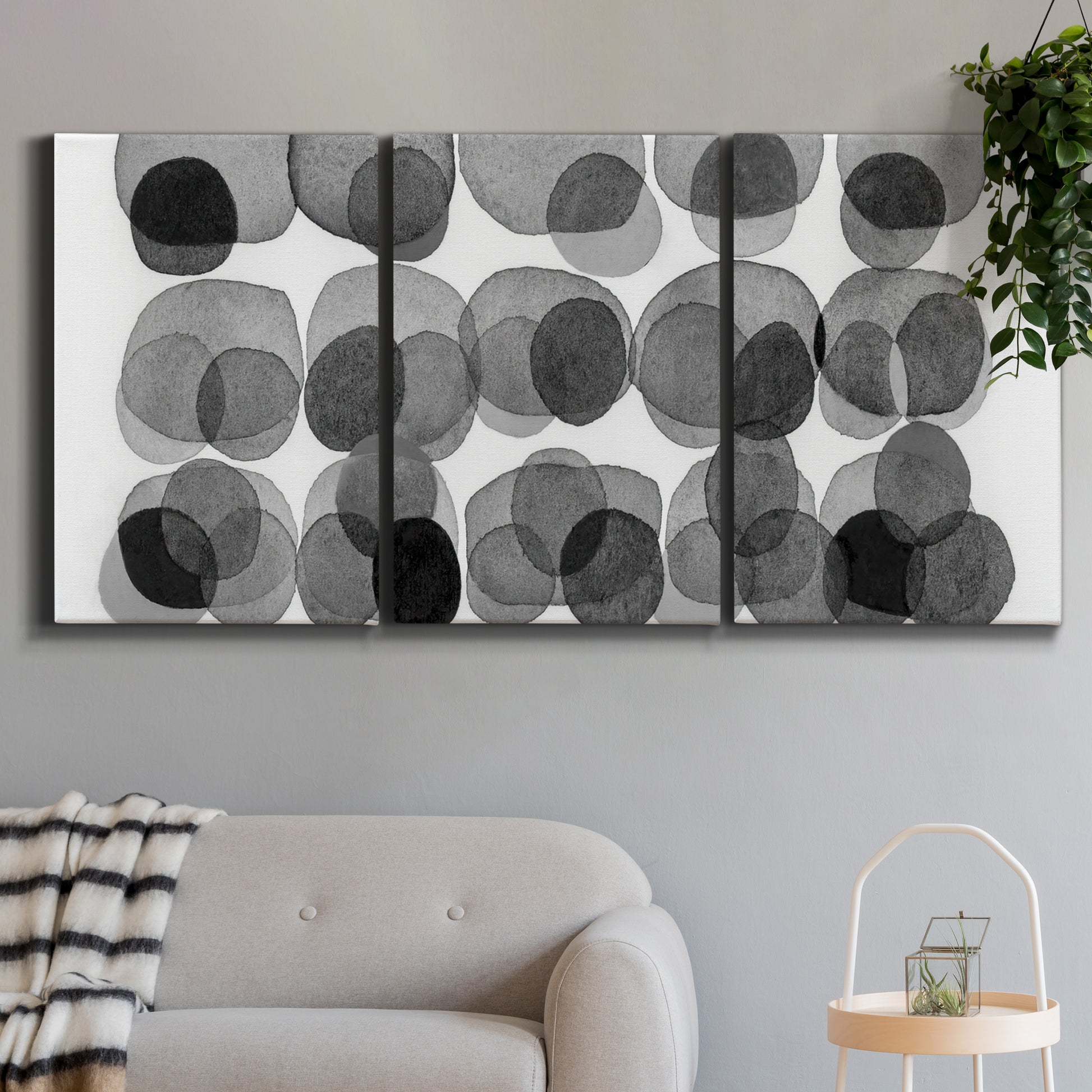 Three-panel canvas wall art featuring geometric abstract watercolor forms, displayed in a modern living room above a sofa.