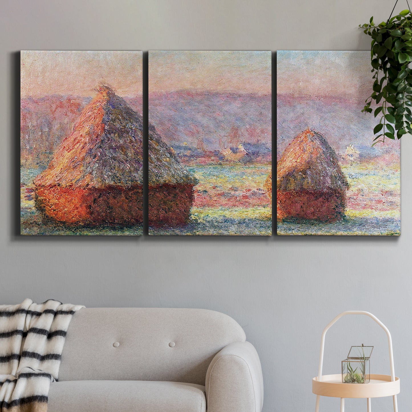Three-panel canvas wall art featuring winter grainstacks glowing at sunset, displayed in a modern living room above a sofa.