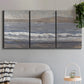 Three-panel canvas wall art featuring shoreline between land and sea, displayed in a modern living room above a sofa.