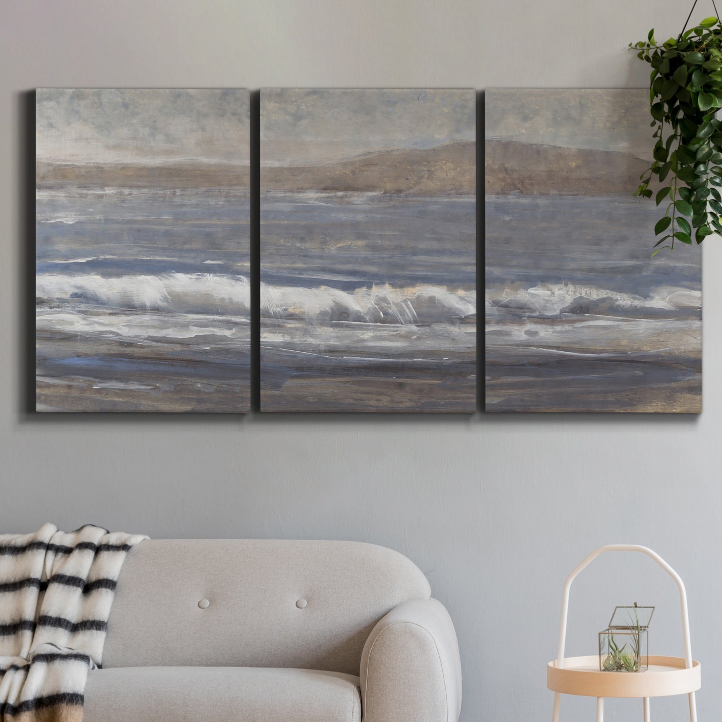 Three-panel canvas wall art featuring shoreline between land and sea, displayed in a modern living room above a sofa.
