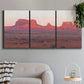 Three-panel canvas wall art featuring red rock desert formations at dusk, displayed in a modern living room above a sofa.