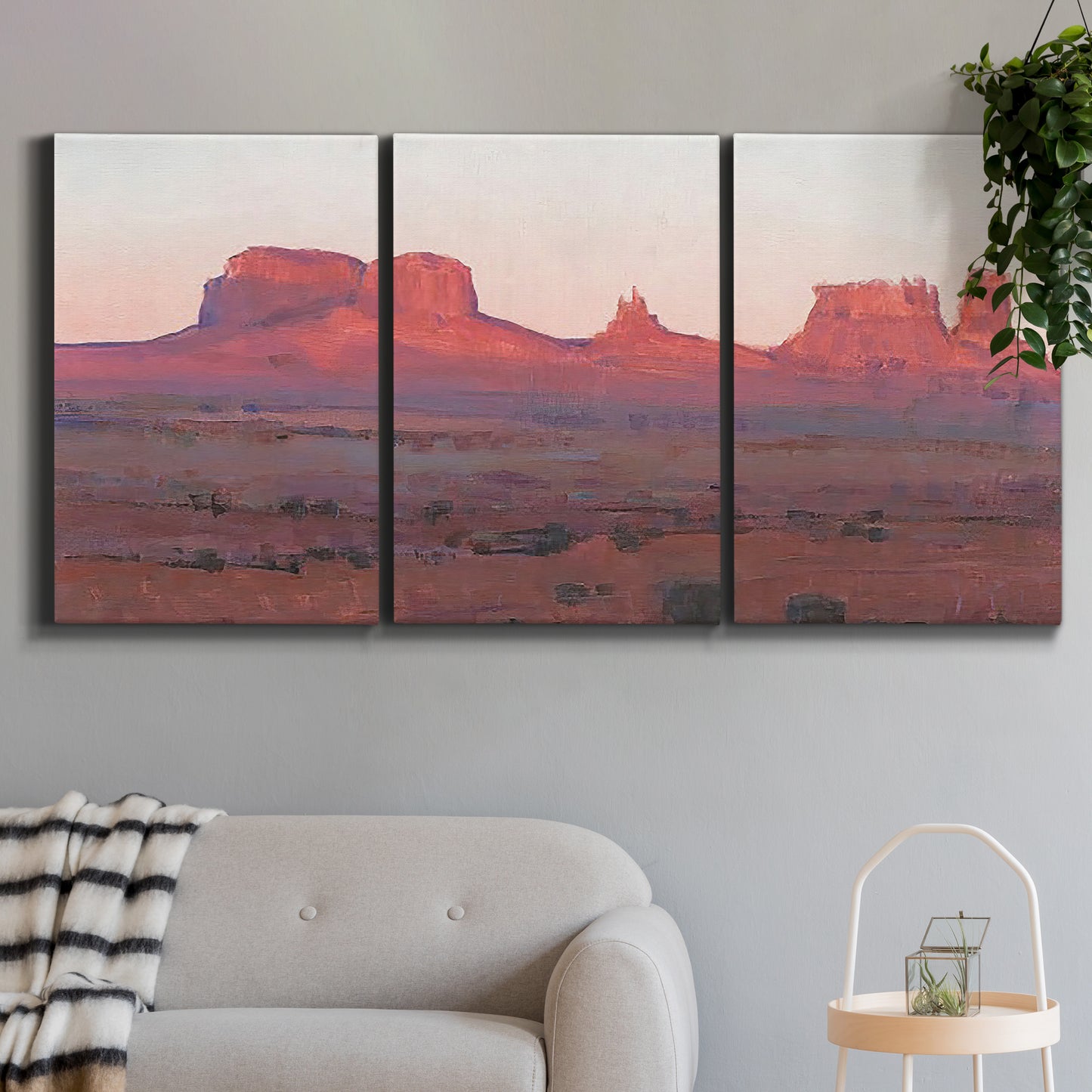 Three-panel canvas wall art featuring red rock desert formations at dusk, displayed in a modern living room above a sofa.