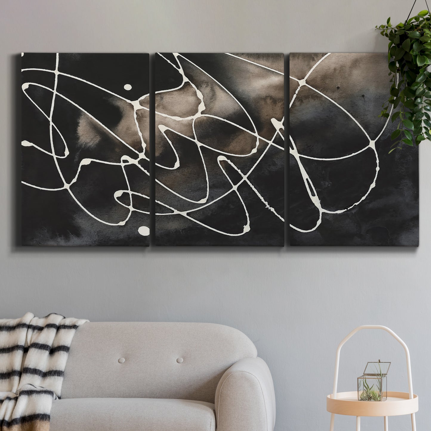 Three-panel canvas wall art featuring dark swirling abstract motion, displayed in a modern living room above a sofa.