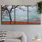 Three-panel canvas wall art featuring coastal trees at evening light, displayed in a modern living room above a sofa.